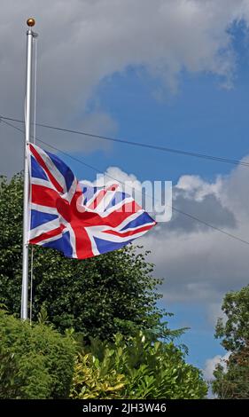 British Flag flying at half mast,  indicating a colleague has passed away, at a British legion / ex-Servicemans Club, Grappenhall, Warrington, UK Stock Photo