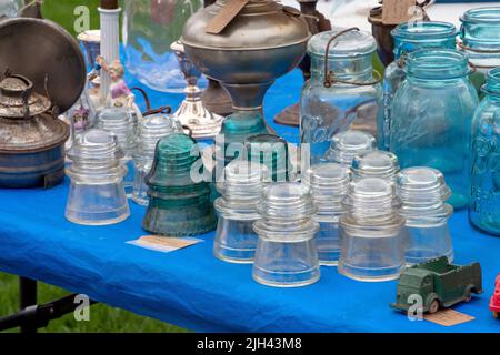 Old oil lamps, glass ball jars and old insulators are some of the collectable items for sale at an antique market outdoors in Michigan USA Stock Photo