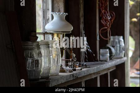 natural light falls on a variety of antiques and junk on a shelf in an old wood barn Stock Photo