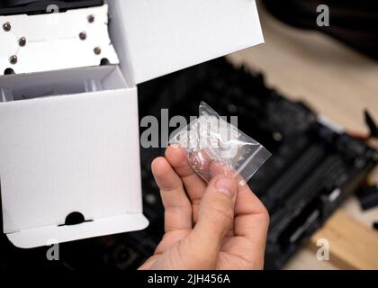 Technician holds in hand mounting legs for installing cooler or motherboard Stock Photo