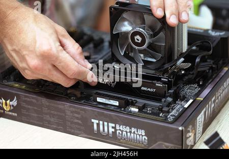 Man installing Furry Beast RAM DDR4 stick and air cooling system of PC processor. PC assembly and modernization. Russia, 17.08.2021 Stock Photo