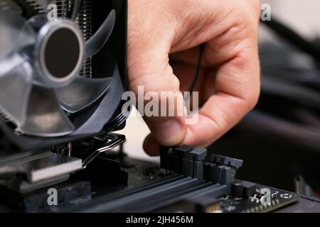 Technician man plugging patch cable from aluminum air-cooled heatsink to processor Stock Photo