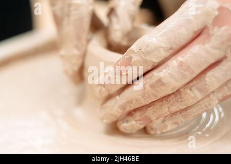 Potters dirty hands on potter wheel close-up Stock Photo