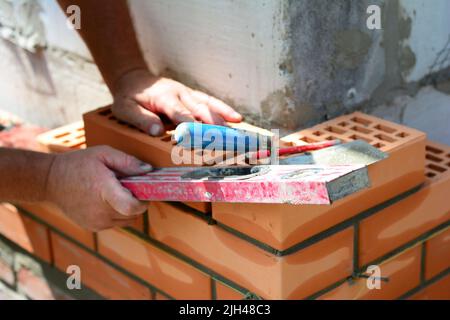 Bricklayer is checking with a spirit level if the corner of a brick wall Stock Photo