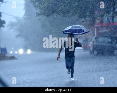 Jammu, Indian-controlled Kashmir. 14th July, 2022. A man dashes with an umbrella in the rain in Jammu, winter capital of Indian-controlled Kashmir, on July 14, 2022. Credit: Str/Xinhua/Alamy Live News Stock Photo