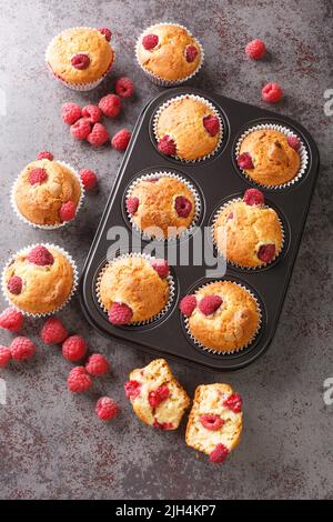 Fresh homemade delicious raspberry muffins closeup on the table. Vertical top view from above Stock Photo