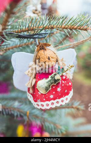 Handmade natural walnut Christmas decoration on Christmas tree. Christmas Angel with wings, star and violin cello. DIY ideas for children. Environment, reuse, upcycling concept. Selective focus Stock Photo