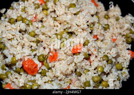 A closeup of hot steamed white rice with vegetables peas and carrots with sliced onion, Chinese cuisine recipe and also of oriental Arabic and China o Stock Photo