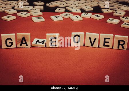 "Game over" phrase composed of wooden tiles with letters on a red felt background Stock Photo