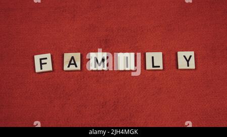 Word 'Family' composed of wooden tiles with letters on a red background Stock Photo