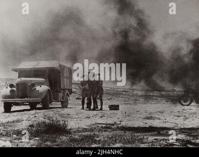 A vintage photo circa 1941 showing two medics from the Royal Army Medical Corps helping a wounded soldier to an Austin K2/Y field ambulance painted with a Red Cross after Axis forces attacked a medical convoy in the Western Desert North Africa Stock Photo