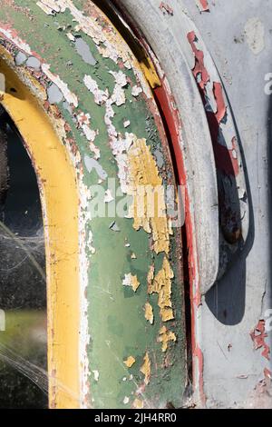 Weathered green, grey, red and yellow peeling paint on an old metal truck cab Stock Photo