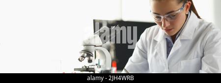 Concentrated chemist worker write down thoughts on investigation project in lab Stock Photo