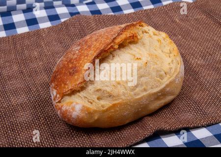 Artisan traditional french bread lies on table covered with rustic style tablecloth Stock Photo