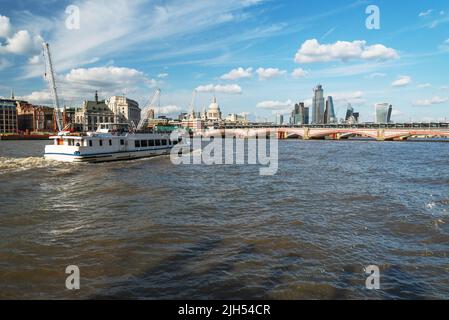 Tourism boat carrying visitors to the city of London to see iconic landmarks along the river,passing the South Bank towards Blackfriars bridge and St. Stock Photo