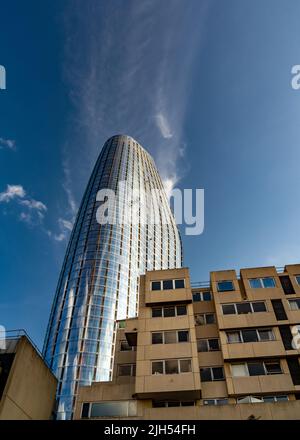 Pointing into blue skies above, on a hot summer day,the tall modern glass plated structure looms over the 1951 built concrete structure, showing archi Stock Photo