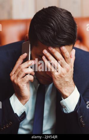 Depressed businessman talking on phone Stock Photo