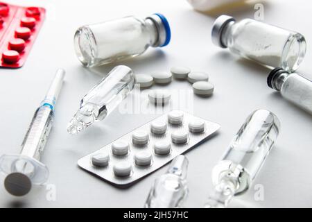 Medicines on a white background: tablets in blister and loose, ampoules with liquid and powder, syringe Stock Photo