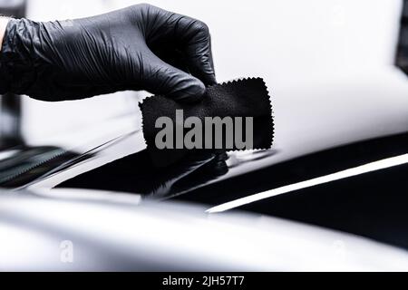 Employee of a car wash or a car detailing studio applies a ceramic coatin Stock Photo