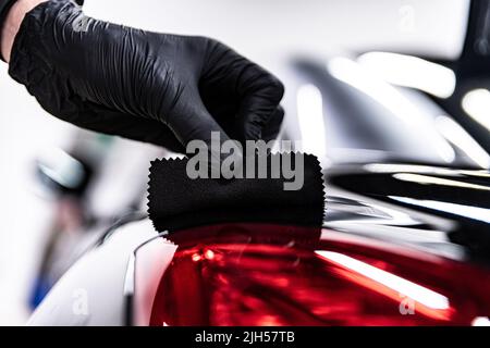 Employee of a car wash or a car detailing studio applies a ceramic coatin Stock Photo