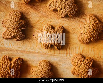 Top view of delicious homemade oatmeal cookies in the form of gingerbread men lying on a wooden kitchen board. Sweet breakfast in the morning. Stock Photo