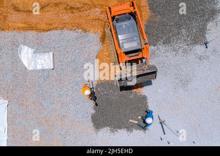 An excavating bucket is in the process of leveling gravel for a building foundation Stock Photo