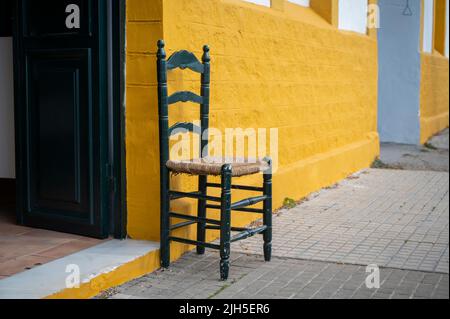 A chair outside an old sherry warehouse and bodega painted yellow, by Gutierrrez Colosia in Puerto de Santa Maria Spain Stock Photo