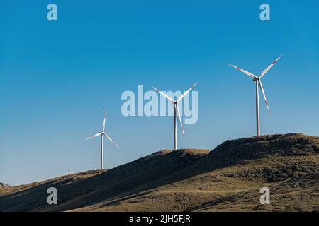 clean electricity producing wind turbine or windmill built on a windy mountain ridge Stock Photo