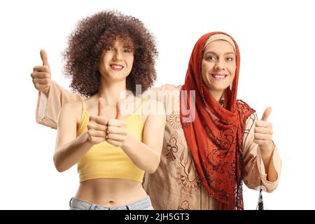 Two young women from different ethnicity showing thumbs up isolated on white background Stock Photo