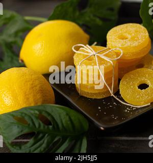 Lemon, orange and grapefruit slices in sugar isolated on a wooden background, close-up. Marmalade sweets. Sweets with citrus flavor. Candies Stock Photo