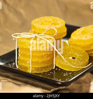 Lemon, orange and grapefruit slices in sugar isolated on a wooden background, close-up. Marmalade sweets. Sweets with citrus flavor. Candies Stock Photo