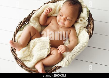 Newborn african baby in wicker basket, flat lay Stock Photo