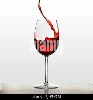 A splash of red wine in a glass for wine. Wine splashes. Drinking water. Alcohol. Isolated on background Stock Photo