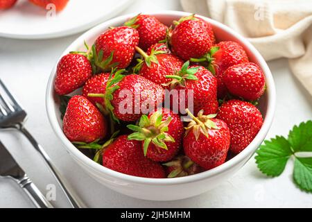 Strawberries in a white bowl on a light background. Stock Photo