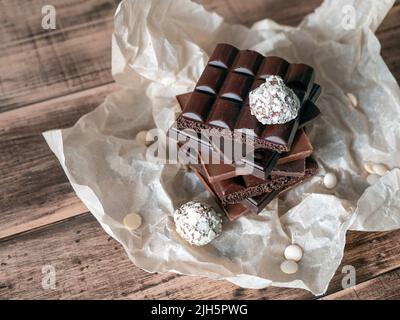 Chocolate bars tower and truffles on wooden surface with copy space. Sweet and delicious food concept Stock Photo