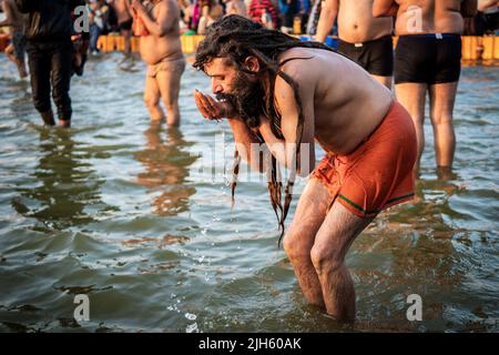 A Hindu man drinks and bathes in the sacred waters at the Triveni Sangam at Kumbh Mela Festival in Allahabad (Prayagraj), Uttar Pradesh, India. Stock Photo