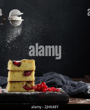 Stack of square slices of baked plum biscuit cake. Powdered sugar sprinkled on top Stock Photo