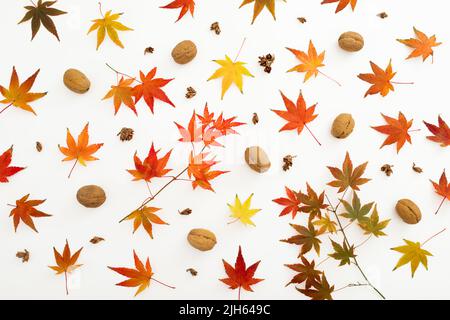 Autumnal pattern with fall leaves and walnut nuts on white background. Flat lay, top view. Thanksgiving day concept. Stock Photo