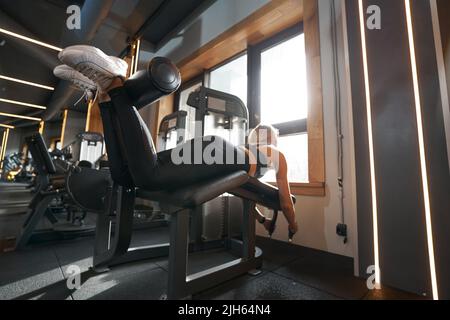 Woman doing hamstring exercise in fitness club Stock Photo