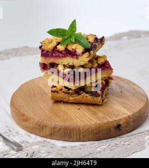 Square slices of cherry crumble lie in a stack on a white background Stock Photo