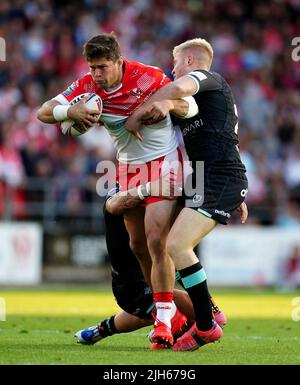 St Helens' Louie McCarthy-Scarsbrook is tackled by Huddersfield Giants' Oliver Wilson and Danny Levi during the Betfred Super League match at the Totally Wicked Stadium, St Helens. Picture date: Friday July 15, 2022. Stock Photo