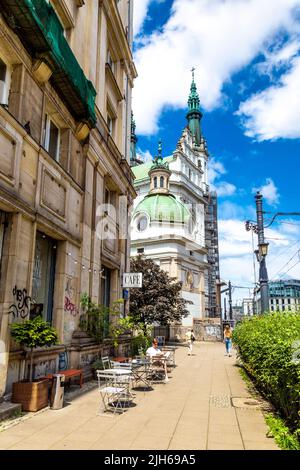 Man sitting sitting outside Ministry of Coffee cafe on Marszałkowska street with Church of the Holiest Saviour in background, Warsaw, Poland Stock Photo