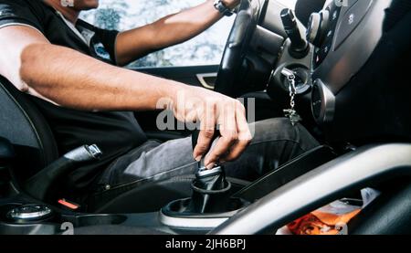 Close-up of driver hand on the gear lever of a car, concept of hand grabbing the gear lever of a car, close-up of hands accelerating on the gear lever Stock Photo
