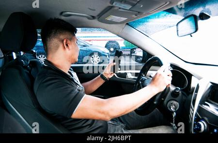 Distracted driver using the cell phone while driving, Man using his phone while driving, Person holding the cell phone and with the other hand the Stock Photo