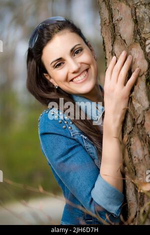 Woman leaning against tree trunk Stock Photo