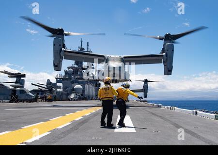 PACIFIC OCEAN (July 13, 2022) Airman Shaion Plummer, from New York City, right, under instruction of Aviation Boatswain’s Mate (Handling) 1st Class Mark Usi, from Spring Valley, California, signals to an MV-22 Osprey attached to Marine Medium Tiltrotor Squadron (VMM) 363 as it takes off from the flight deck of Wasp-class amphibious assault ship USS Essex (LHD 2) during Rim of the Pacific (RIMPAC) 2022. Twenty-six nations, 38 ships, four submarines, more than 170 aircraft and 25,000 personnel are participating in RIMPAC from June 29 to Aug. 4 in and around the Hawaiian Islands and Southern Cali Stock Photo
