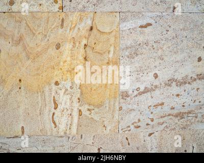 Yellow-brown material. Church cladding. Background from stone tiles. Interesting texture. Temple walls. Stock Photo