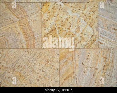 Yellow-brown material. Church cladding. Background from stone tiles. Interesting texture. Temple walls. Stock Photo