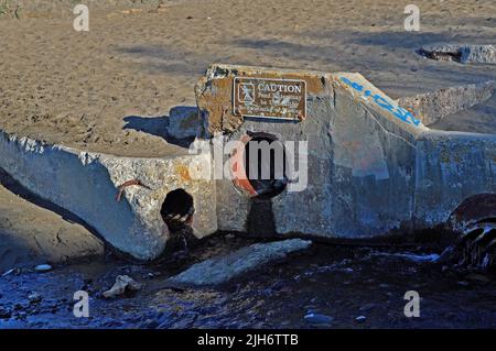 fresh water Lobos Creek draining onto Baker Beach. Caution sign that the pond water may be  unhealthy and no swimming or wading,  San Francisco, California Stock Photo