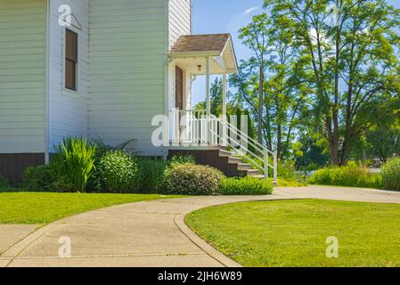 Entrance into small traditional church in rural. Exterior of a Little White Country Church on a Sunny Day Stock Photo